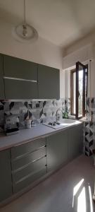 a kitchen with green cabinets and a sink and a window at La Poltrona del Diavolo in Montenero