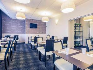 a dining room with tables and chairs and a tv at Mercure Tours Centre Gare et Congrès in Tours