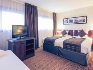 a hotel room with two beds and a flat screen tv at Mercure Tours Centre Gare et Congrès in Tours +45 photos