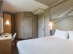 a bedroom with a large white bed and a desk at ibis Genève Aéroport in Geneva