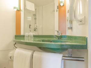 a bathroom with a green sink and a mirror at ibis Genève Aéroport in Geneva