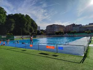 a large swimming pool with people in the water at Apartamento familiar acogedor in Ordes