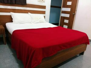 a bed with a red blanket on top of it at Pacio Residency in Kanchipuram