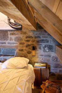 a bedroom with a bed and a stone wall at Buron du Tournel, un écrin d'exception in Le Lioran