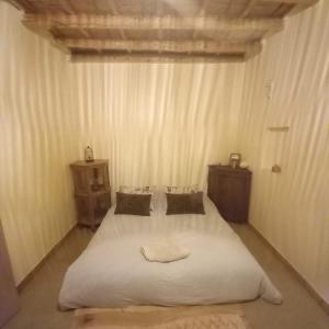 a bedroom with a white bed and two night stands at Gîte berbère in Tagadirt Alkadi +2 photos