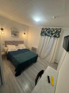 a bedroom with a bed with a green comforter at Hôtel du Champs de Mars in Béziers