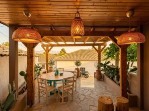 a patio with a table and chairs under a wooden pergola at Villa Kalimoukos in Corfu