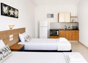two beds in a small room with a kitchen at H Stella Apartments & Rooms in Kalamitsi