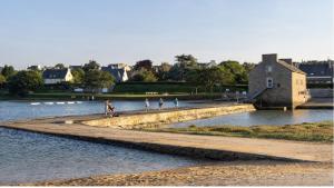 a group of people walking on a path in the water at Le paradis sur mer in Paimpol