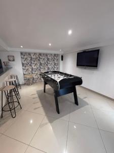 a black foosball table in a room with a tv at Appartement Carreira in LʼIsle-Adam