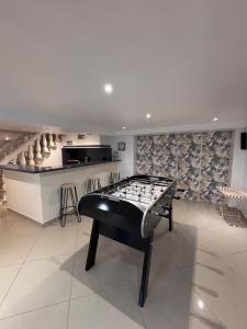 a ping pong table in a room with a bar at Appartement Carreira in LʼIsle-Adam
