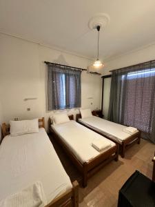 two beds in a room with two windows at Hotel TSAPARAS in Alíartos +14 photos