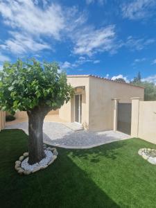 a house with a tree in the front yard at L'escale Provençale in Pierrelatte