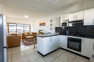 a kitchen with white cabinets and a living room at Safi Luxury Self-Catering Suite 8 in East London