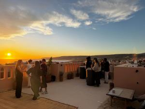 a group of people standing on a roof watching the sunset at Get Salty Guesthouse in Tamraght Ouzdar