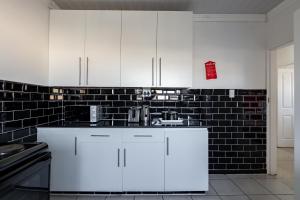 a kitchen with white cabinets and a black tile wall at Safi Elegant Self-catering Suite 5 in East London