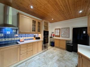 a large kitchen with wooden cabinets and tile floors at Glenrigh House - Main Residence for 7 people in Onich +30 photos