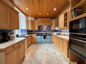 a kitchen with wooden cabinets and a blue stove at Glenrigh House - Main Residence for 7 people in Onich