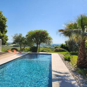 a swimming pool in a yard with a palm tree at Aux Coteaux d'Aussac in L Honor De Cos