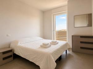 a white bedroom with a bed and a window at Casa Mamma Etna in Riposto