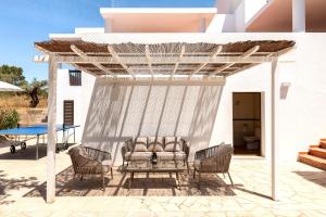 a pergola with chairs and a table on a patio at New! Villa Can Mila in Sant Joan de Labritja
