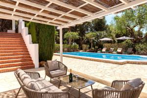 a patio with chairs and a table and a pool at New! Villa Can Mila in Sant Joan de Labritja