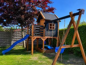a playground with a swing and a house at Willa Kapitańska i Willa Marynarska in Łeba