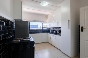 a kitchen with white cabinets and a black refrigerator at Safi Luxury Apartment 6 - 2 bedroom in East London