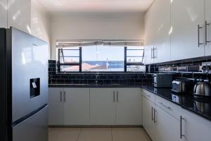 a kitchen with white cabinets and a large window at Safi Luxury Apartment 6 - 2 bedroom in East London +4 photos