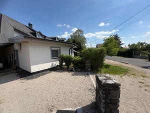 a small white house with a yard next to a street at Puzzle Haus in Gyenesdiás