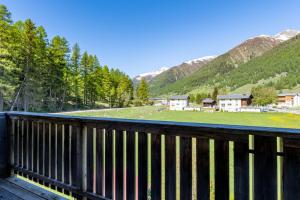 a wooden deck with a view of a field and mountains at Ferienwohnung Aegimatte in Ulrichen
