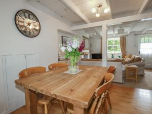a dining room table with chairs and a vase of flowers at Gwynn Cottage in Bodmin