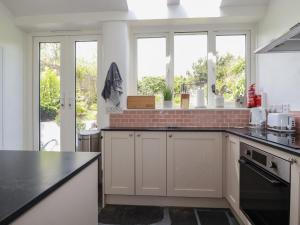 a kitchen with white cabinets and a black counter top at Gwynn Cottage in Bodmin +9 photos