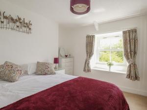 a white bedroom with a bed and a window at Gwynn Cottage in Bodmin
