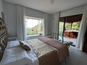 a bedroom with a bed and a large window at Recanto Bougainville ST in Santa Teresa