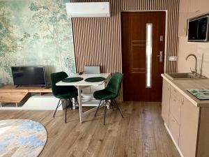 a kitchen with a table and two green chairs at Puzzle Haus in Gyenesdiás +8 photos