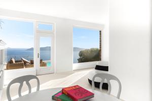 a white room with a table and chairs and a large window at Neraé Santorini in Imerovigli