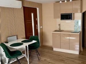 a kitchen with a table and two green chairs at Puzzle Haus in Gyenesdiás