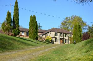 a house on a hill with trees and a dirt road at La Cour d'Arblade in Arblade-le-Haut