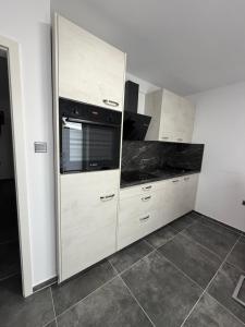 a kitchen with white cabinets and a black appliance at Moderne 2 Zimmer Wohnung Küche und Bad im Zentrum in Merzig