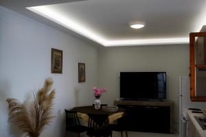 a living room with a television and a table with chairs at Gridia Apartment in Chios