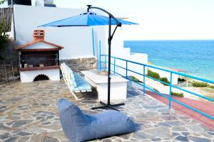 a chair and an umbrella on a patio next to the ocean at Gridia Apartment in Chios