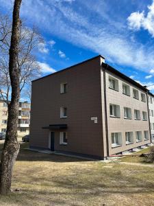 a large building with a tree in front of it at Skersgatvio Apartmentai in Zarasai