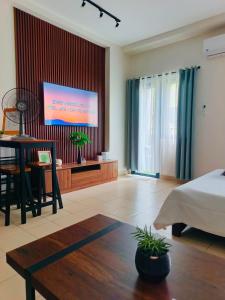 a bedroom with a bed and a table and a screen at Hills Residences by JuJu Staycation in Manila
