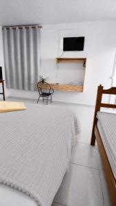 a bedroom with a bed and a chair and a television at Estádia aconchegante! in Vilhena