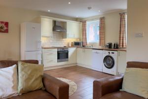a kitchen with white cabinets and a washer and dryer at Cottages by the Moat in Hassocks