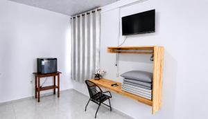 a room with a desk with a tv and a chair at Estádia aconchegante! in Vilhena