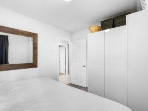 a white bedroom with a bed and a mirror at Mountain Edge 1020 our Holiday Home in Kimberley