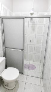 a white bathroom with a shower with a toilet at Estádia aconchegante! in Vilhena +5 photos
