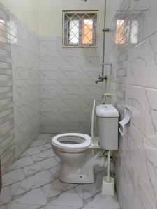 a white bathroom with a toilet and a window at Iconic lux living in Malindi